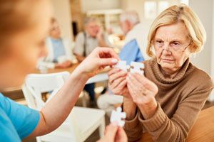 Frau hilft älteren Dame beim Zusammensetzen von Puzzelteilen