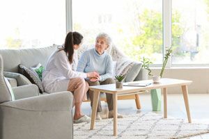 Frau redet mit älterer Dame auf dem Sofa