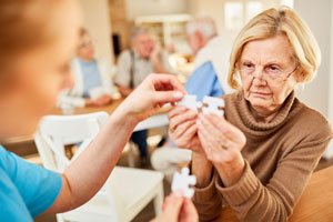 Frau hilft älteren Dame beim Zusammensetzen von Puzzelteilen